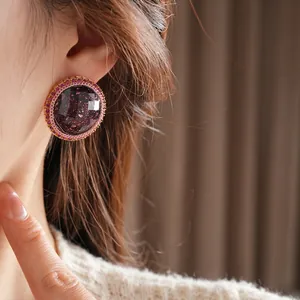 Deep purple resin stud earring with sparkling rhinestones on model with beige sweater