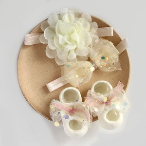 Close-up of cream baby headband and sock set with sequins and floral mesh details