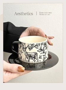 Detail showing the ceramic coffee cup with elk and forest hand-painted patterns