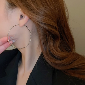 Close-up of a model wearing minimalist large silver geometric hoop earrings in a sleek design