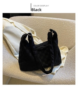 Detail of black woven pattern tote bag on sofa featuring textured canvas material