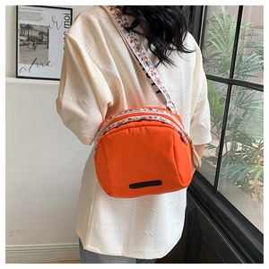 Detail of waterproof nylon crossbody bag with ethnic embroidered strap and zipper pockets