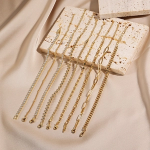 9-piece gold chain bracelet set with tennis, bead and heart links on silk background