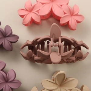 Close-up of matte floral claw clips in assorted pastel colors including pink and beige