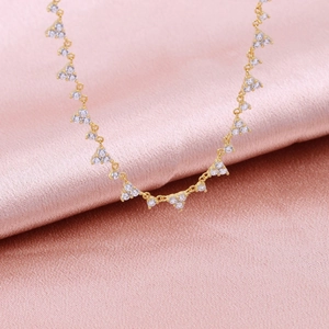 Macro view of gold S925 silver necklace with white cubic zirconia triangle clusters