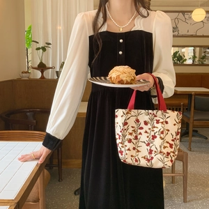 Detailed shot of corduroy floral lunch bag with red handles and metal magnetic closure