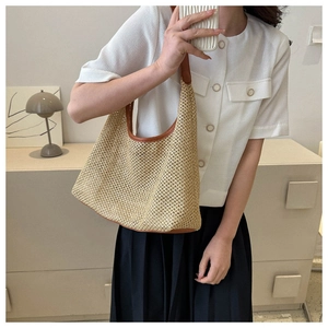 Close-up of woven straw tote bag with brown leather trim shown on model