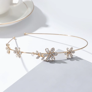 Détails d'un serre-tête vintage doré avec fleurs en strass et perle élégante