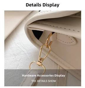 Close-up of golden metal D-ring and lobster clasp on cream leather shoulder strap