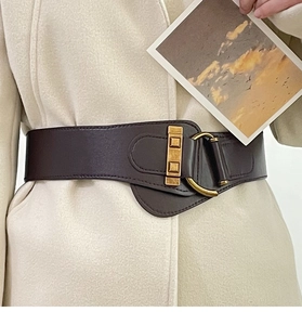 Close-up of a wide dark brown leather corset belt with vintage gold buckle on a coat
