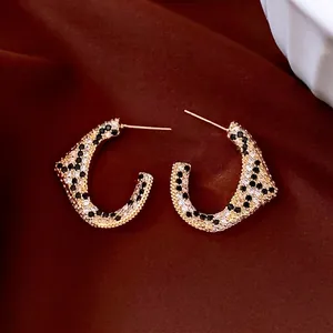 Vintage C-shaped earrings plated in 18K gold with leopard pattern zircons on velvet