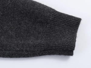 Close-up of ribbed knit cuffs and plush charcoal grey wool texture on cardigan sleeve