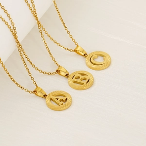 Detail view of 18K gold plated alphabet pendants A, B and C with brushed metal texture