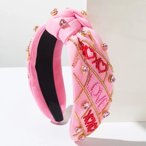 Dettaglio fascia rosa con gemme a cuore e ricami di perline con scritta XOXO