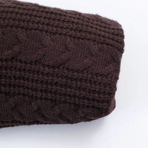 Dettaglio macro della trama in maglia a trecce marrone scuro di un maglione con cappuccio
