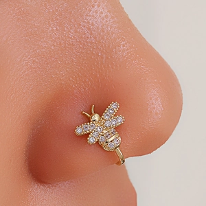 Macro shot of gold bee-shaped nose cuff with zircon stones on a model nose