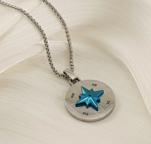 Macro shot of a silver compass pendant with a blue star detail on white silk fabric