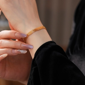 Gros plan d'un bracelet en maille tissée dorée avec des couches de métal complexes