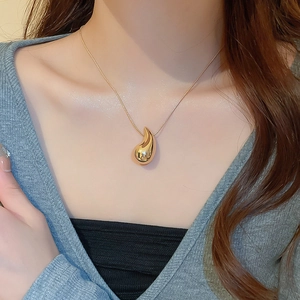 Close-up of a golden teardrop pendant necklace worn by a model for a stylish metal look