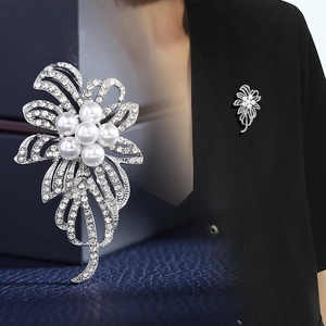 Broche florale argentée exquise avec perles blanches et strass sur un coffret bleu