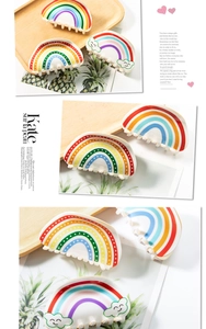 Detailed view of colorful rainbow hair claws with cloud accents on a wooden display