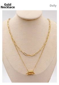 Detail of a layered gold titanium necklace with a ribbed cylinder pendant on a jewelry bust