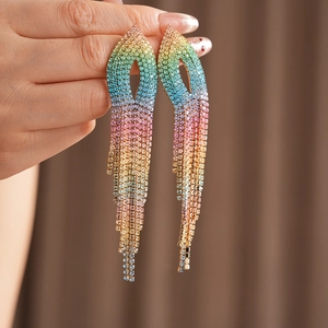 Detailed view of rainbow gradient rhinestone tassel earrings held in hand for scale