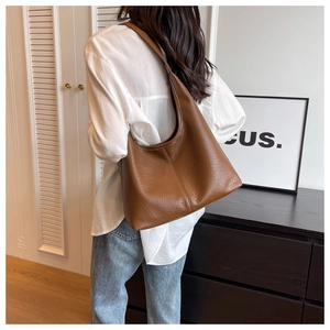 Brown lychee grain PU leather tote bag worn by a model in a cozy interior scene