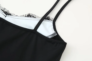 Gedetailleerde close-up van fijn wimperkant en dunne bandjes op een zwarte bodycon jurk