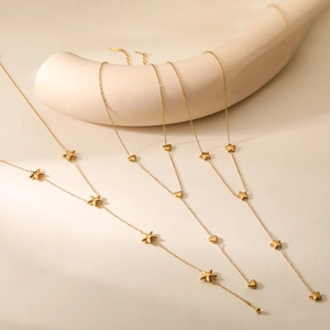 Minimalist layered gold necklace with heart and star pendants hanging on display stand