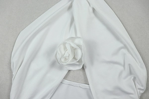 Detailed view of the elegant 3D folded fabric flower on white halter dress