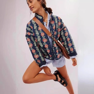 Women's dark blue quilted jacket featuring bright orange floral prints and a stand collar