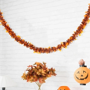 Detail of 2m Halloween tinsel garland with orange pumpkin charms on white brick wall
