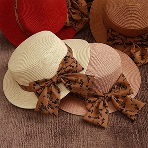 Detailed top view of straw sun hats in four colors with floral ribbon bow decorations