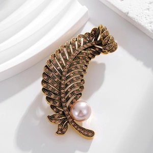Elegant gold feather brooch with pink crystals and a large pearl for suit decoration
