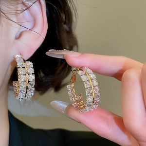Détail rapproché de boucles d'oreilles dorées à double rangée et cristaux brillants