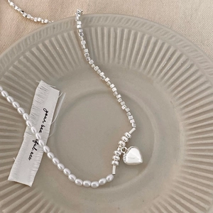 Macro shot of pearl and silver chain necklace with a polished metal heart pendant
