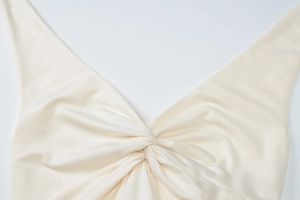 Close-up of beige summer dress featuring a deep V-neckline and stylish center twist detail