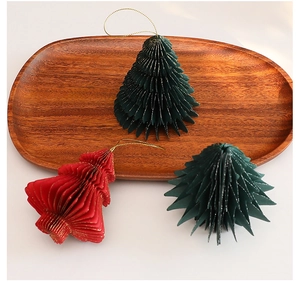 Close-up of honeycomb paper Christmas tree ornaments with gold glitter edges on wooden tray