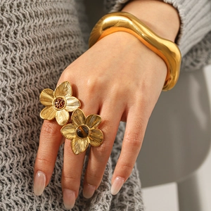 Golden flower tiger eye ring and wavy metal bangle set on model with knitwear background