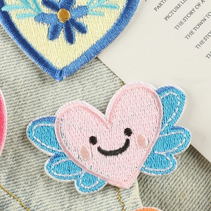 Toppe ricamate a forma di cuore con ali e fiori su un elegante sfondo di jeans