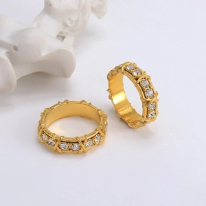 Elegant gold crossover rings with clear zircon stones on a white luxury background