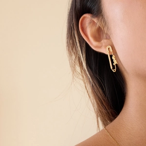 Gros plan d'une boucle d'oreille trombone dorée avec zircons blancs et texte Love