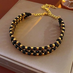 Detail of double-layer black and gold beaded choker necklace with adjustable chain and clasp