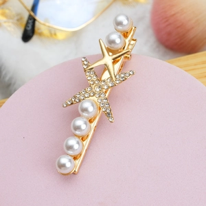 Détail d'une pince à cheveux étoile de mer dorée avec perles et strass scintillants