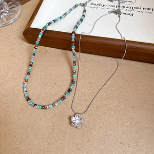 Detailed macro view of layered beaded necklace set with silver flower pendant on vintage paper