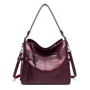 Close-up of wine red leather tote bag showing metallic zippers and tassel detail