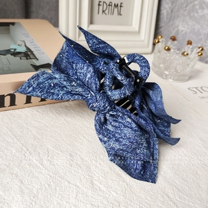 Blue denim bow hair claw clip with shimmering accents and durable plastic shark grip