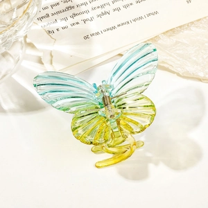 Macro detail of butterfly hair claw clip with teal and yellow gradient finish