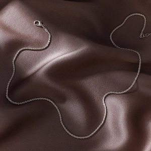 Minimalist silver water wave chain necklace displayed on dark chocolate silk background